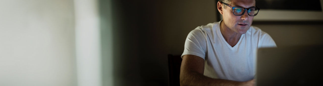 man with glasses on looking at laptop screen