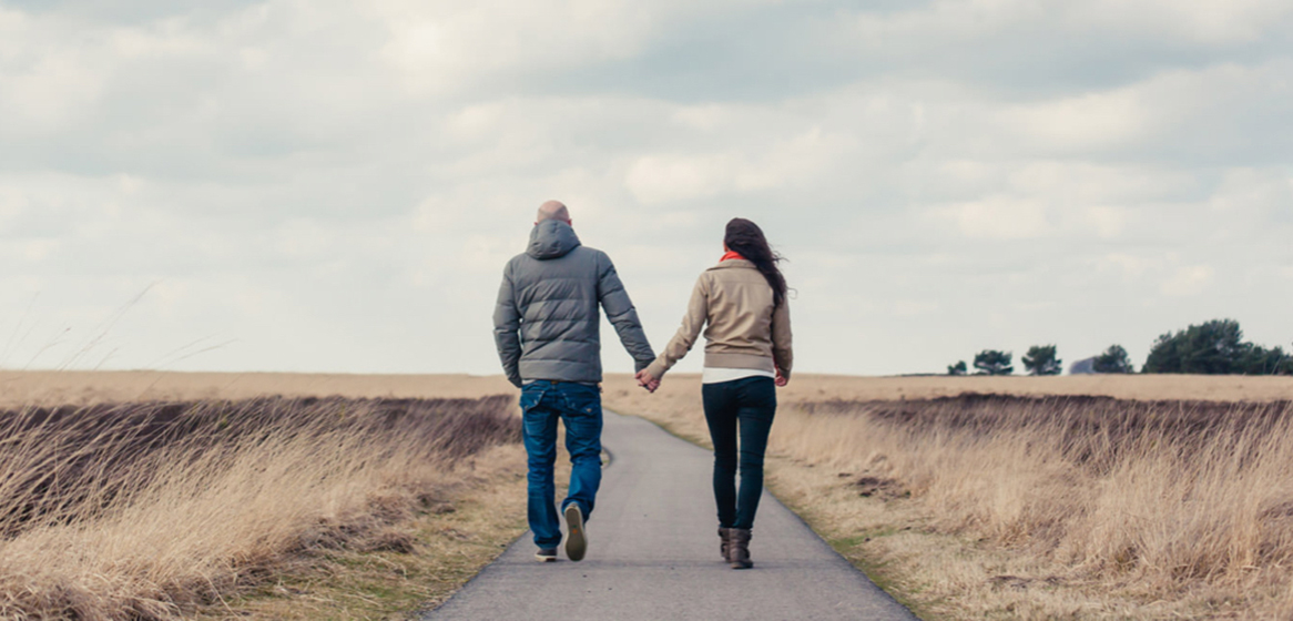 Two people walking on a paved trail.