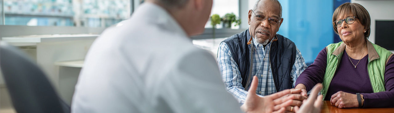 Man and woman talking to a physician in an office.